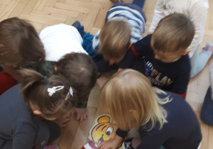 Grupa dzieci układa z drewnianych puzzli Myszkę Miki.